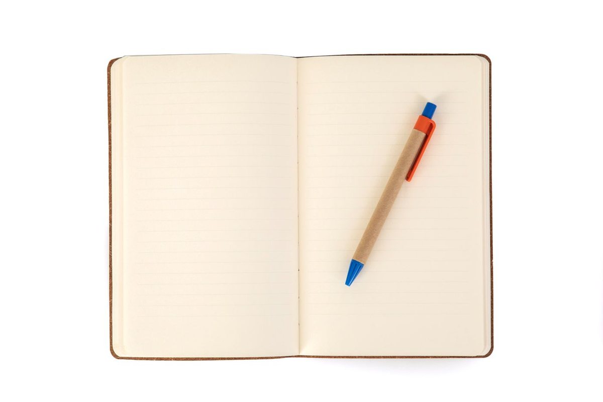 机の上に開いた、まだ何も書かれていないノートと鉛筆