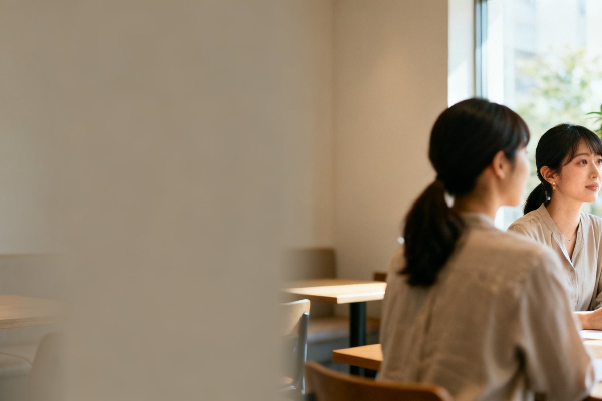 明るい部屋で、並んで座って話をしている二人の女性